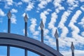 Forged door against the blue sky with lines of clouds