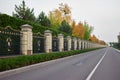Forged fence and decorative bushes along empty road.