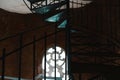 Forged iron twisted stairs with reflection on a red brick wall, handrails of the old vintage building, window with ornament