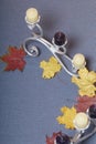 Forged metal candlestick with candles. Fallen autumn leaves of yellow and red are scattered on the surface. Royalty Free Stock Photo