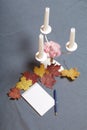 Forged metal candlestick with candles. There is an open notepad and a pen. Fallen autumn leaves of yellow and red are scattered on Royalty Free Stock Photo