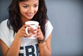 Forget love, fall in coffee. Studio shot of a young woman drinking a cup of coffee against a gray background.