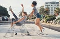 Forget your problems or let your friends make you forget. a young woman pushing her friend around on the promenade in a