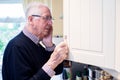 Forgetful Senior Man With Dementia Looking In Cupboard At Home Royalty Free Stock Photo