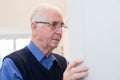 Forgetful Senior Man With Dementia Looking In Cupboard At Home Royalty Free Stock Photo