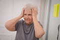 Forgetful senior woman near mirror with reminder note indoors. Age-related memory impairment