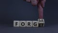 Forgive and forget symbol. Businessman turns a wooden cube and changes the word forgive to forget. Beautiful grey background, copy