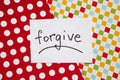 Forgive - word on white real paper with colorful background, relationship concept