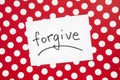 Forgive - word on white real paper with red and dots background, religion and relationship