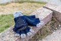 Forgotten blue and gray colored childrens gloves lying on a stone in a park