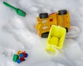 Forgotten children`s toys green scoop, typewriter, yellow bucket, yellow big car in the snow. close-up. without people