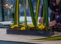 Forist arranging flowewrs and leaves in metal container