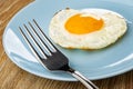 Fork in blue plate with fried egg on wooden table Royalty Free Stock Photo