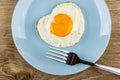 Fork in blue plate with fried egg on wooden table. Top view Royalty Free Stock Photo