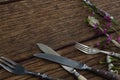 Fork, butter knife and spoon with flower on wooden table Royalty Free Stock Photo