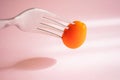 Fork with cherry tomato. Close-up, pastel pink background. Royalty Free Stock Photo