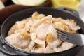 Fork with delicious dumpling (varenyk) and fried onions over plate, closeup