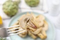 Fork with delicious pickled artichoke over table, closeup