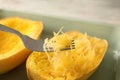 Fork with flesh over cooked spaghetti squash in baking dish