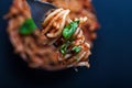 Fork full of twirled italian spaghetti with a bolognese meat sauce and basil over a plate of pasta with tomato sauce. Royalty Free Stock Photo