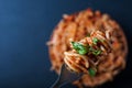 Fork full of twirled italian spaghetti with a bolognese meat sauce and basil over a plate of pasta tomato sauce. Royalty Free Stock Photo