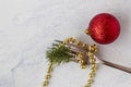 fork with gold beads and a branch of a Christmas tree next to a red New Year's ball on a white textured background Royalty Free Stock Photo