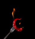 Fork impale to red hot chili on black background