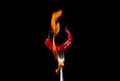 Fork impale to red hot chili on black background
