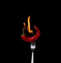 Fork impale to red hot chili on black background