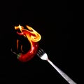 Fork impale to red hot chili on black Royalty Free Stock Photo