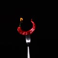 Fork impale to red hot chili on black Royalty Free Stock Photo
