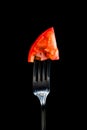 Fork with an injected tomato on a black background