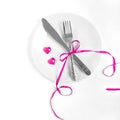 Fork and knife decorated with pink ribbon and decorative hearts on the plate Royalty Free Stock Photo