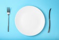 fork, knife and empty plate on color blue background, top view Royalty Free Stock Photo