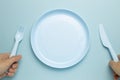 Fork, knife and empty plate on sky blue background Royalty Free Stock Photo