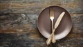 Fork and knife on empty plate, wooden table. Flat lay Royalty Free Stock Photo