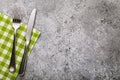 Fork, knife and napkin of green color in the left part of a table with texture of concrete, top view Royalty Free Stock Photo