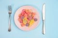 Fork, knife and pink plate with gummy candies on blue Royalty Free Stock Photo