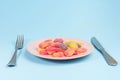 Fork, knife and pink plate with gummy candies on blue Royalty Free Stock Photo