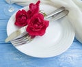 Fork, knife, plate, flower rose table decoration anniversary festive concept dating on a blue wooden background, romantic design Royalty Free Stock Photo