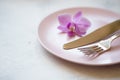 Fork and knife with a purple orchid flower on a pink plate Royalty Free Stock Photo