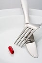 Fork, knife and a single red pill on a plate Royalty Free Stock Photo