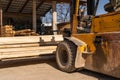 Fork lifter at warehouse lifting timber planks in sunny day no people