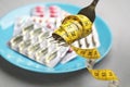 Fork with measuring tape and blurred pills on background, closeup. Weight loss Royalty Free Stock Photo