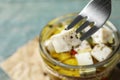 Fork with pickled feta cheese over jar on blue table Royalty Free Stock Photo