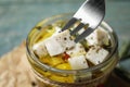Fork with pickled feta cheese over jar on blue table Royalty Free Stock Photo