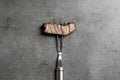 Fork with piece of delicious barbecued meat on gray background