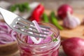Fork with slice of pickled onion over jar on table Royalty Free Stock Photo