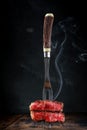 Fork with sliced and steaming grilled beef fillet steak on a wooden table Royalty Free Stock Photo