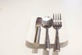 Fork, spoon and butter knife on a white plate Royalty Free Stock Photo